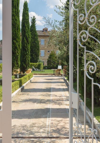 Giardino curato con alberi e vialetto, visto attraverso un cancello decorativo.