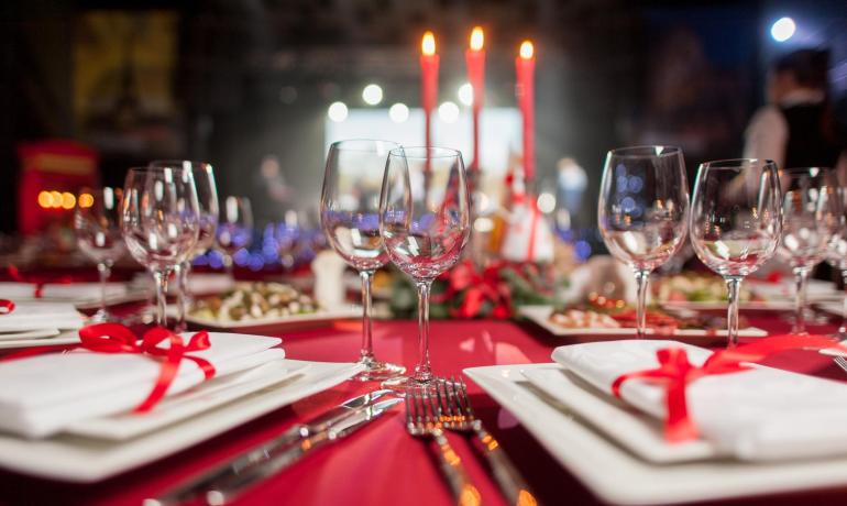 Tavola elegante con bicchieri e candele rosse, atmosfera festiva.