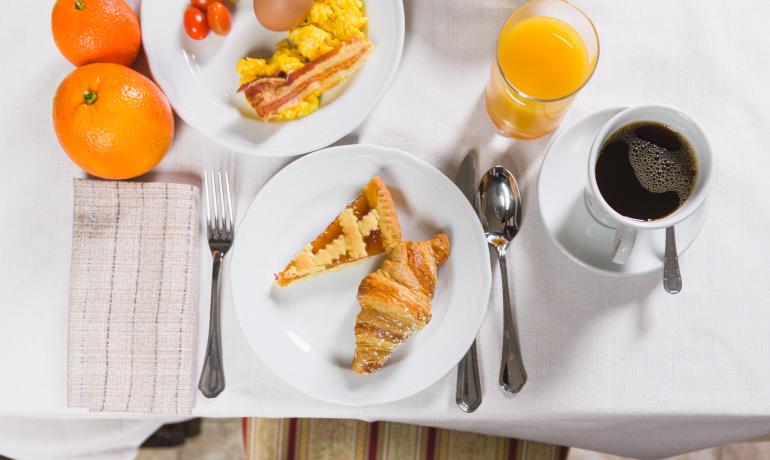 Colazione con croissant, torta, uova e caffè.