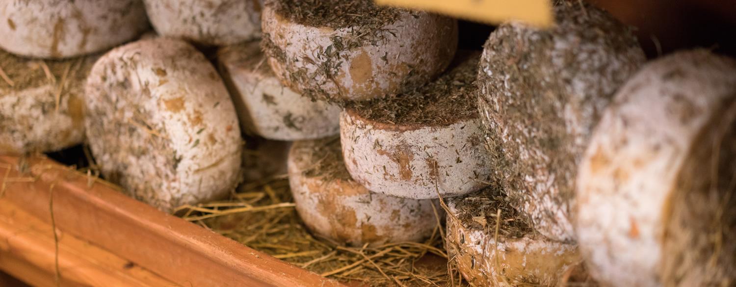 Aged cheeses on straw with aromatic herbs.