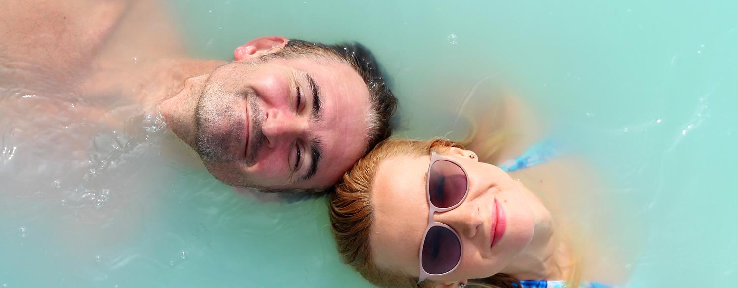 Two people smiling while floating in clear water.