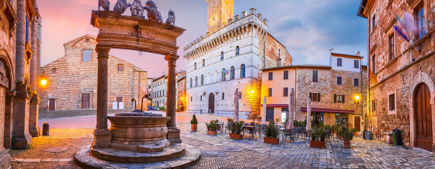 Historic square with well and stone buildings at sunset.